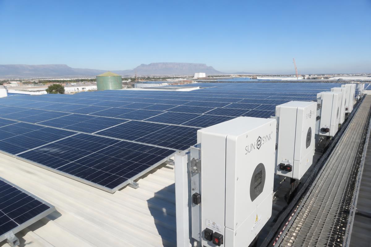 Rooftop solar photovoltaic array with wall-mounted inverters on an industrial warehouse